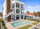 A backyard pool with a tanning ledge, outdoor kitchen, and stairs leading to upper floors with black metal balconies at 109 Punta Vista Dr, St Pete Beach, FL 33706