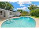 Backyard pool with a well-kept lawn and a house with a dark roof, offering a refreshing outdoor space at 11361 88Th Ave, Seminole, FL 33772