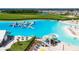 Aerial view of the community's lagoon with an aqua park, sandy beach, and surrounding homes and green spaces at 16927 April Plush Dr, Wimauma, FL 33598