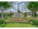 Landscaped entrance to Medley Clubhouse featuring a colorful flower bed and vibrant green lawn at 16927 April Plush Dr, Wimauma, FL 33598