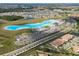 A wide, aerial view of a neighborhood with a Personal-made lagoon, parking, and a green space at 16927 April Plush Dr, Wimauma, FL 33598
