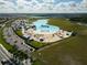 Aerial view of a turquoise lagoon with a beach, waterpark, parking and a green space at 16927 April Plush Dr, Wimauma, FL 33598