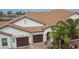 Home with dark garages and a red tiled roof surrounded by palm trees at 16927 April Plush Dr, Wimauma, FL 33598