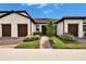 Charming home featuring a well-manicured lawn, symmetrical shrubbery and brick pathway at 16927 April Plush Dr, Wimauma, FL 33598