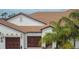 Home exterior showcasing dark brown garages and mature palm trees at 16927 April Plush Dr, Wimauma, FL 33598