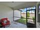 Screened in lanai with a red chair looking out to a grass backyard with palm trees at 16927 April Plush Dr, Wimauma, FL 33598