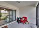 Screened lanai with a red chair with bags looking out through the sliding glass door at 16927 April Plush Dr, Wimauma, FL 33598