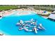 Aerial view of water park in turquoise lagoon with sandy beach, slides, sunshades, and other resort amenities at 16927 April Plush Dr, Wimauma, FL 33598