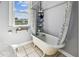 Classic clawfoot bathtub with shower in a bright bathroom with tiled floors and a window at 2408 Linsey St, Tampa, FL 33605