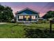 Charming blue home at dusk featuring a welcoming front porch, manicured lawn, and vibrant yellow door at 2408 Linsey St, Tampa, FL 33605