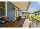 Covered front porch with wood floors and seating, overlooking a well maintained front yard at 2408 Linsey St, Tampa, FL 33605