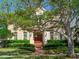 Charming home exterior featuring a manicured lawn, lush green bushes, a large mature tree, and a brick path leading to a grand wooden door at 2927 W Bayshore Ct, Tampa, FL 33611