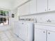 Bright laundry room with washer, dryer, sink, and ample storage cabinets at 2927 W Bayshore Ct, Tampa, FL 33611