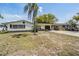 Modest single story home with palm tree and black shutters, set on a lot with a long driveway at 3340 Columbus Dr, Holiday, FL 34691