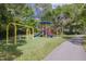 Community playground with swings, slides, and climbing structures, surrounded by lush greenery at 4206 Preserve Pl, Palm Harbor, FL 34685