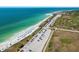 Aerial view of a white sand beach and turquoise ocean water with rows of cars in parking lot at 5 Island Park Pl # 305, Dunedin, FL 34698