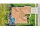 Aerial view of the home highlighting the roof, landscaped yard with garden, and screened-in pool at 5137 Epping Ln, Zephyrhills, FL 33541