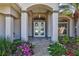 Elegant front entrance with decorative glass doors, stone walkway, and colorful flower beds at 5137 Epping Ln, Zephyrhills, FL 33541