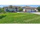 Charming home featuring a well-manicured lawn, lush landscaping, and a three-car garage at 5137 Epping Ln, Zephyrhills, FL 33541