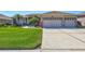 Charming home featuring a well-manicured lawn, lush landscaping, and a three-car garage at 5137 Epping Ln, Zephyrhills, FL 33541