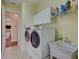 Bright laundry room with white cabinets, modern appliances, a utility sink and access to the kitchen at 5137 Epping Ln, Zephyrhills, FL 33541