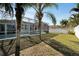 Backyard view of the screened-in pool and patio area, surrounded by lush landscaping and a white fence at 527 Manns Harbor Dr, Apollo Beach, FL 33572