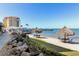 Waterfront dining and beach featuring tiki umbrellas near the water, plus an elevated restaurant overlooking the water at 6265 Sun Blvd # 1201, St Petersburg, FL 33715