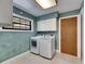 Laundry room with a modern washer and dryer, white cabinets and trim, a window and tan tile floor at 6603 Seabird Way, Apollo Beach, FL 33572