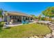 Expansive backyard showcasing the pool, covered patio, stone bar, outdoor seating, and lush landscaping at 714 Bayshore Dr, Tarpon Springs, FL 34689