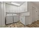 Convenient laundry room with modern washer, dryer, ample cabinet space, and unique stone patterned flooring at 714 Bayshore Dr, Tarpon Springs, FL 34689
