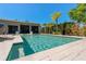 Sparkling in-ground pool with a sun shelf surrounded by a travertine deck and tropical landscaping at 714 Bayshore Dr, Tarpon Springs, FL 34689