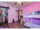 Pink-walled bedroom featuring hardwood floors, a bunk bed, and an organized closet at 15204 Westminister Ave, Clearwater, FL 33760