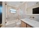 Bright bathroom with white subway tile, bronze fixtures, glass shower and wood vanity at 1981 Briarwood St, Dunedin, FL 34698