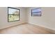 Empty bedroom featuring light hardwood floors and two large windows at 1981 Briarwood St, Dunedin, FL 34698