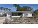 Charming white one-story home featuring a screened-in porch, attached garage, and a partially fenced yard at 2122 Holiday Dr, Holiday, FL 34691
