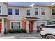 Charming townhome featuring colorful stucco, manicured landscaping, and covered entryway to the vibrant red front door at 263 Alexander Woods Dr, Plant City, FL 33563