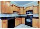 Open kitchen displays wood cabinets, granite countertops, and modern black appliances at 263 Alexander Woods Dr, Plant City, FL 33563