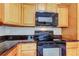 Close-up of kitchen boasts wood cabinets, dark countertops, and modern black appliances at 263 Alexander Woods Dr, Plant City, FL 33563
