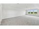 Bright bedroom featuring carpet, white walls, and a set of three windows at 31651 Westbury Estates Ave, Wesley Chapel, FL 33545