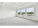Spacious bedroom featuring plush carpeting, tray ceiling, and large windows with picturesque water views at 31651 Westbury Estates Ave, Wesley Chapel, FL 33545