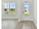 Sunlit living room with stylish wood flooring and a clear view of the front yard through large windows at 31651 Westbury Estates Ave, Wesley Chapel, FL 33545