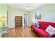 Bright bedroom features a ceiling fan, laminate floors, and a red futon near the window for relaxing at 33357 Westwood Dr, Ridge Manor, FL 33523