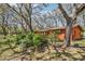 Charming single-story home with an orange exterior, surrounded by lush trees and a beautiful garden at 33357 Westwood Dr, Ridge Manor, FL 33523