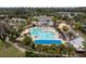 Aerial view of community pool, jacuzzi, lounge chairs, and clubhouse surrounded by palm trees at 4787 Majestic Hills Loop, Brooksville, FL 34601