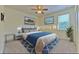 Comfortable staged bedroom featuring a ceiling fan, vibrant artwork, and stylish blue bedding at 5409 Conch Shell Pl, Apollo Beach, FL 33572