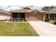 Charming one-story home boasts a well-manicured lawn, a screened-in porch, and a two-car garage at 5664 Legend Hills Ln, Spring Hill, FL 34609