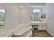 A bright, well-lit bathroom with double vanities, soaking tub, walk-in shower, and neutral fixtures at 604 Mcdaniel St, Sun City Center, FL 33573