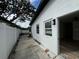 View of the backyard with newly painted white stucco walls, small plants, and a sliding glass door entrance at 7608 Lakeside Blvd, Tampa, FL 33614