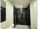 Bathroom featuring black marble tile and a shower with rainfall showerhead, pedestal sink and grey pebble flooring at 7608 Lakeside Blvd, Tampa, FL 33614