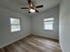Bright bedroom with wood flooring, ceiling fan, and natural light from two windows at 7608 Lakeside Blvd, Tampa, FL 33614
